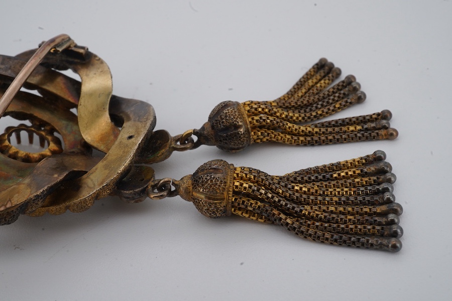 A Victorian opal brooch, mid 19th century, of knotted design in textured gold, set with a cabochon opal, suspending two tassels, length 7cm, gross weight 14 grams